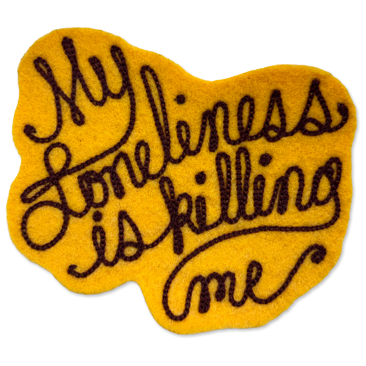 A yellow felt patch with dark brown embroidered text reading 'My loneliness is killing me' on a plain white background.