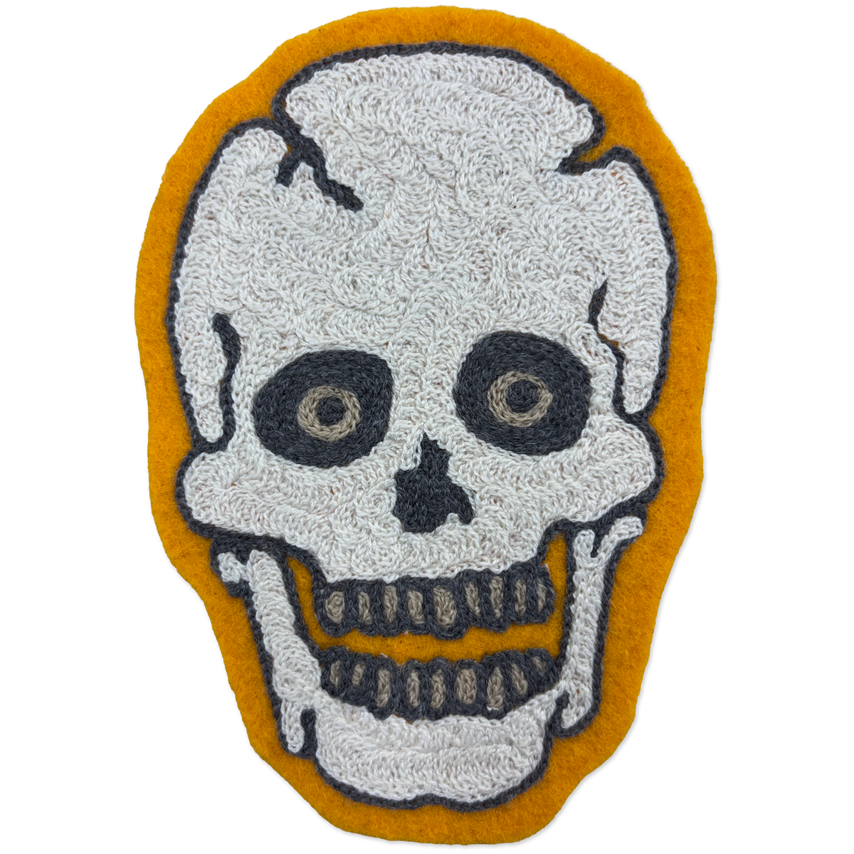 A skull-shaped chainstitch patch with a textured white skull design outlined in black, set against a mustard yellow background.