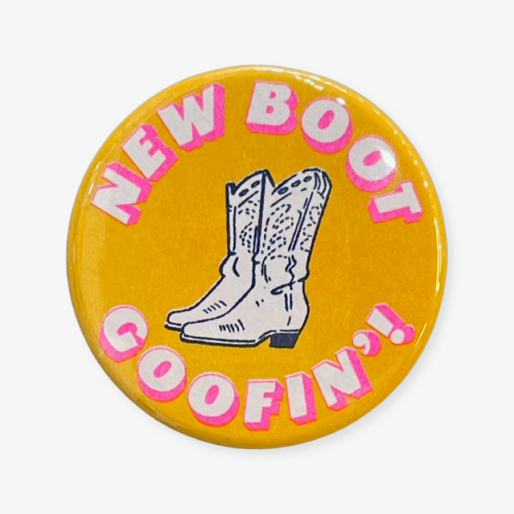 Yellow button with pink and white lettering, and an illustration of cowboy boots.