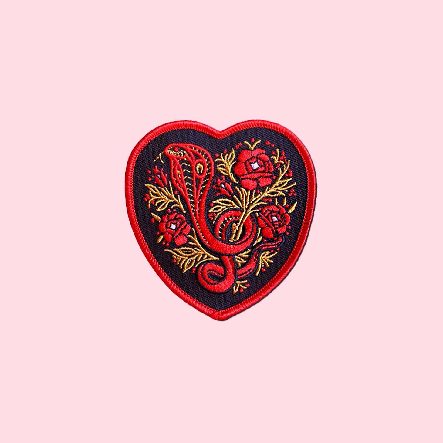 Black, red, and gold heart-shaped patch with cobra and flowers design